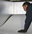 A contractor installing TerraBlock™ floor insulation in a Niagara Falls crawl space