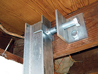 Securing the i-beam system to the top of the floor joist in a foundation wall repair in Niagara Falls.