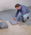 Contractors installing basement subfloor tiles and matting on a concrete basement floor in Guelph, Ontario